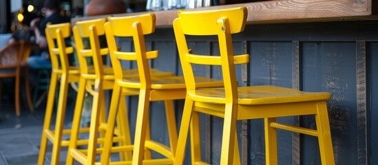 Multiple bright chairs in yellow color placed neatly in rows along a wooden counter inside a bar
