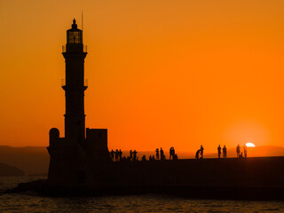 Old lighthouse in a port town at sunset (Chania, Crete, Greece) - obrazy, fototapety, plakaty