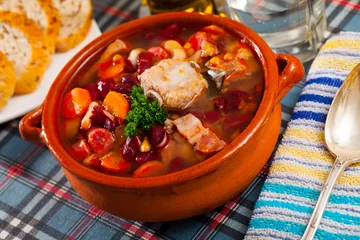 Poster Braised pork meat on bone with red kidney beans served with fresh parsley in pottery.. © JackF