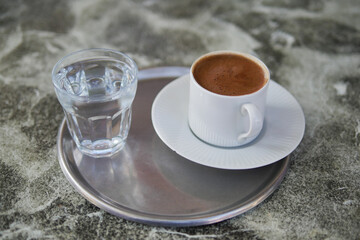a cup of turkish coffee and glass of water on tiles background 