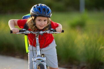 Little kid boy ride a bike in the park. Kid cycling on bicycle. Happy smiling child in helmet...