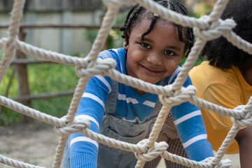 Close up, African child boy climbing a rope ladder and smile at the camera