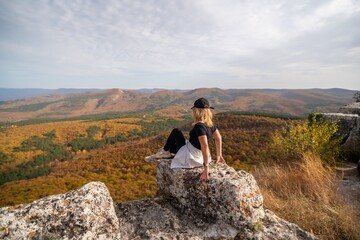 Naklejka na ściany i meble woman on mountain peak looking in beautiful mountain valley in autumn. Landscape with sporty young woman, blu sky in fall. Hiking. Nature