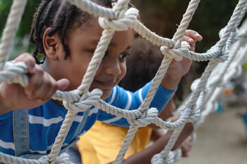 Close up, African child boy climbing a rope ladder, selective focus