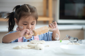Little girl was playing with the bread dough that was placed on the table, she wants to try making...