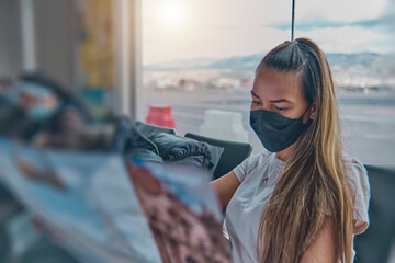 A woman wearing a mask is reading a travel brochure, view guide tourist