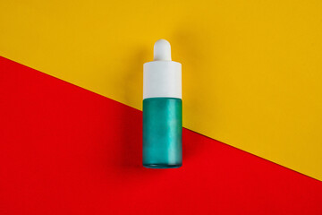 Blue glass cosmetic bottle, Skin care or sunscreen cosmetic on yellow and red background.