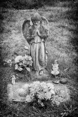 Moody image of angel standing above a child's grave.