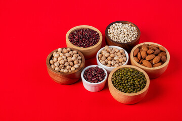 Mung beans, Red kidney beans, Chickpeas source and peeled barley in white cup on spoon wooden on red background
