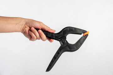 Obraz premium Black plastic spring clamp in hand isolated on white background