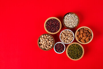 Mung beans, Red kidney beans, Chickpeas source and peeled barley in white cup on spoon wooden on red background