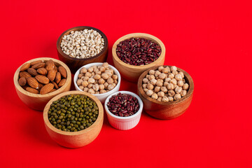 Mung beans, Red kidney beans, Chickpeas source and peeled barley in white cup on spoon wooden on red background