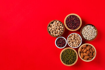 Mung beans, Red kidney beans, Chickpeas source and peeled barley in white cup on spoon wooden on red background