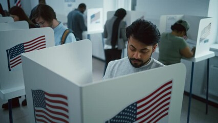 Indian man, American citizen votes in booth in polling station office. National Election Day in the United States. Political races of US presidential candidates. Civic duty and patriotism. Dolly shot.
