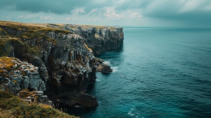 A cliff towering above a body of water in the middle, creating a striking landscape view. The water...