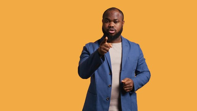 Disappointed african american man admonishing friend over debacle, isolated over studio background. Upset BIPOC person in disagreement with mate, pointing finger and lecturing him, camera B