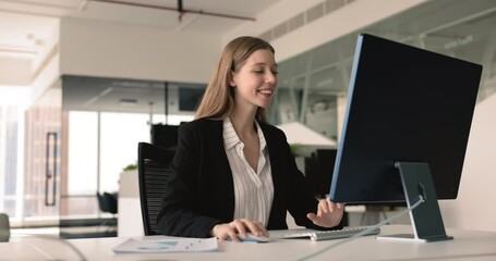 Smiling businesswoman, financial analytics or marketer make research working in modern corporate office seated at desk use personal computer. Prepare report, do on-line presentation or sales analysis