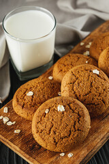 oatmeal cookies with a glass of milk on a black wooden rustic background