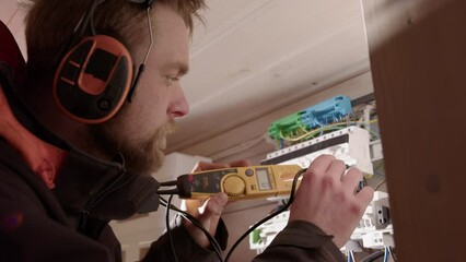 Licensed electrician use voltmeter to test current at residential electric panel