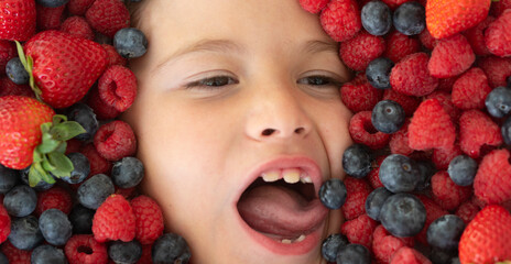 Mix of berries. Kids face with fresh berries fruits. Assorted mix of berries strawberry, blueberry, raspberry, blackberry on background. Healthy nutrition berries for kids. Funny kids face close up. - 786829785