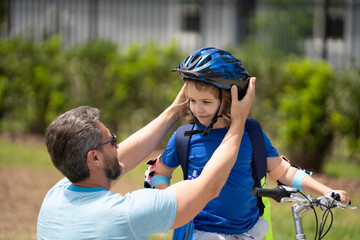 Fathers day concept. Father and son in bike helmet learning ride bicycle. Father and son on bicycle on summer day outdoor. Father helping his son to wear a cycling helmet. Happy fathers day. - 786830136