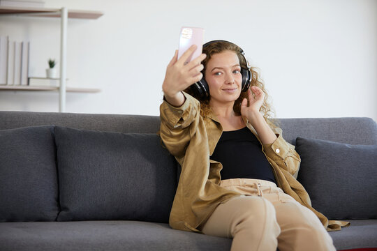 young woman with headphones and listen to music from smartphone
