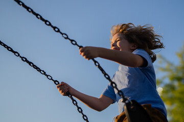 Kid swinging high. Adorable blonde child having fun on a swing on playground. Happy kid swinging on playground area. Summer playground. Child swinging high. - 786831161