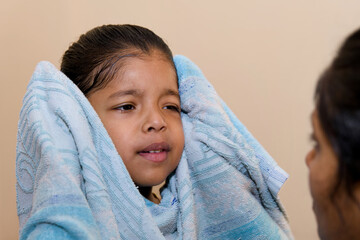 Cute little girl wrapped in a towel after washing her face at home