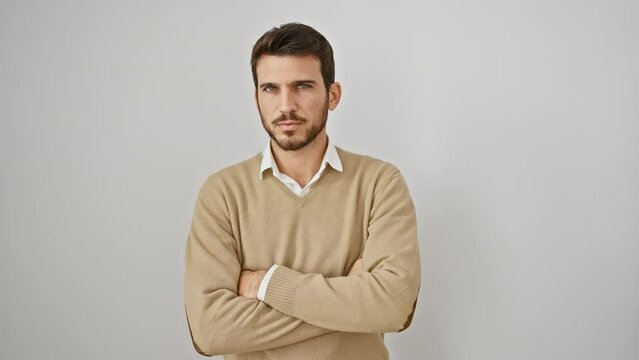 Nervously doubting young hispanic man sporting a sweater, stands isolated on a white background. with a skeptical face and crossed arms, shows a grumpy, disapproving expression