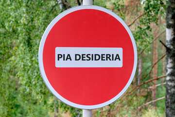PIA DESIDERIAPIA the phrase in Latin means Good intentions traffic is prohibited on the sign against the background of the forest