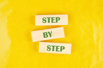 Concept Step by Step text on wooden blocks on a yellow background