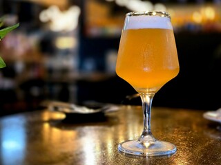 Cold beer in a glass, Wooden table and dark interior of bar.