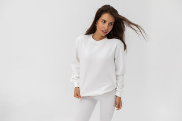 Beautiful brunette girl in a white sweatshirt and leggings