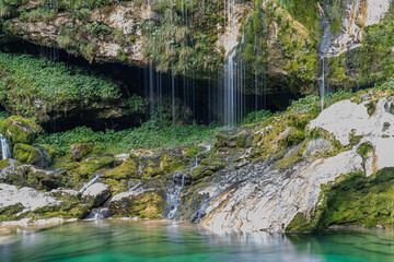 Detailaufnahme des Virje Wasserfall in Slowenien, Wasser läuft über grünbewachsene Felsen