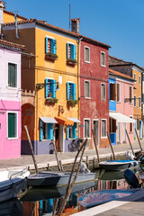 Fototapeta na wymiar Detailaufnahme der bunten Häuserfront in Burano (Italien), Boote schwimmen im Kanal, Häuser spiegeln sich im Wasse