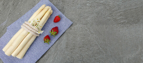 White asparagus with strawberries on a kitchen towel with space for text.