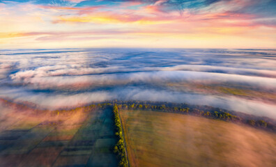 Cultivated fields covered by thick fog. Funtastic rural scene of Ukrainian countryside at sunrise....
