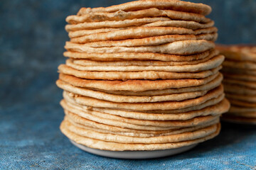 Flatbread lavash, chapati, naan, heap of tortilla on a blue background Homemade flatbread stacked.