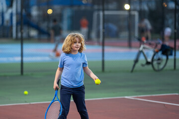 Child boy playing tennis on court. Blonde little boy hit tennis ball with tennis racket. Active exercise for kids. Summer activities for children. Child learning to play tennis. Sport Kid hitting Ball