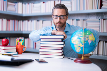 Portrait of teacher with book in library classroom. Handsome teacher in university library. Teachers Day. Teacher giving classes. School teacher in library. Tutor at college library on bookshelf. - 786872543
