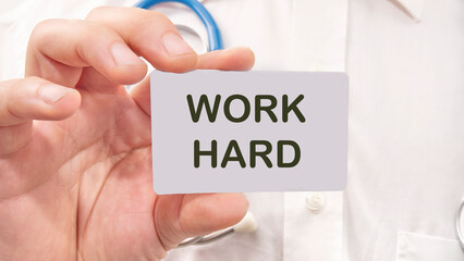 Work Hard the inscription on the business card is in the hands of a man in a white shirt