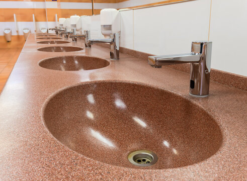 Row of washbasins with automatic taps and ceramic sinks in a public toilet