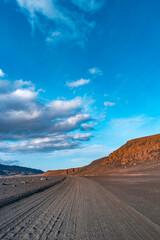 Cover page with dirt road near Herdubreid volcano in the lifeless volcanic Lunar desert in Highlands, with stones and rocks thrown by volcanic eruptions, Iceland, summer, blue sky, sunset
