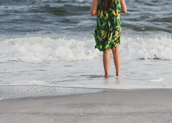 young girl standing in the ocean wearing green dress