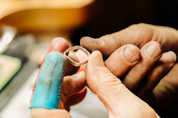 Close up of jewelers hands inspecting fine silver bezel