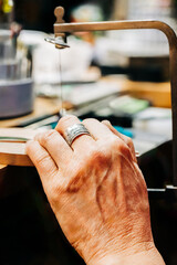 Close up of jewelers hand using jewelers saw