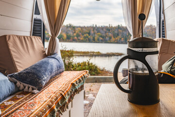 Cozy van life with French press coffee and serene lake view
