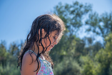 Young girl with curly wet hair swimming at Russian river