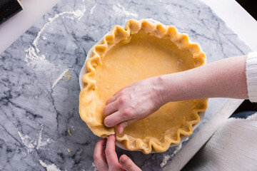 Preparing a fluted pie crust on a marble countertop