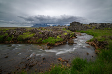 Wild river with mountains and stormy clouds in Iceland